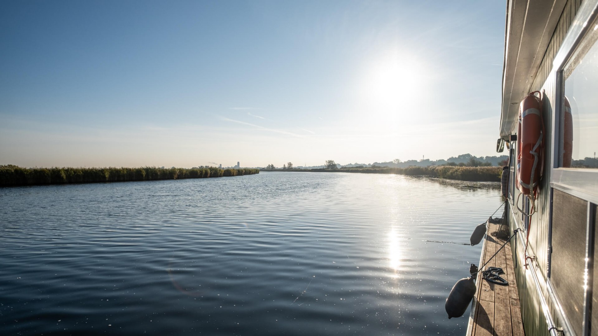 Woonboot op de Peene in de stralende zon en rustig water in de richting van Anklam.
