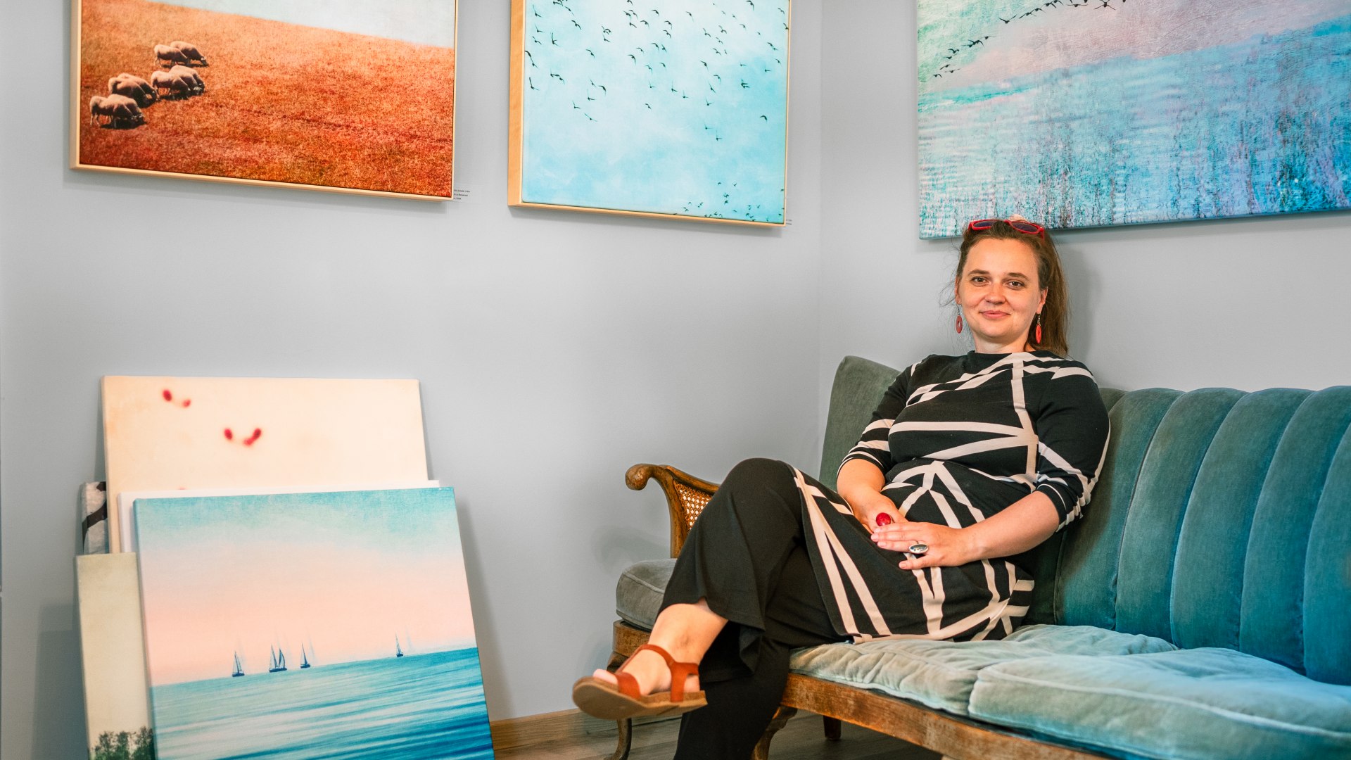 Claudia is also a photo artist - she sits on the couch with paintings all around her.