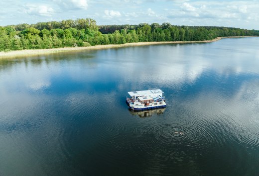Dwie łodzie mieszkalne leżą obok siebie na jeziorze, a obok nich pływa człowiek.