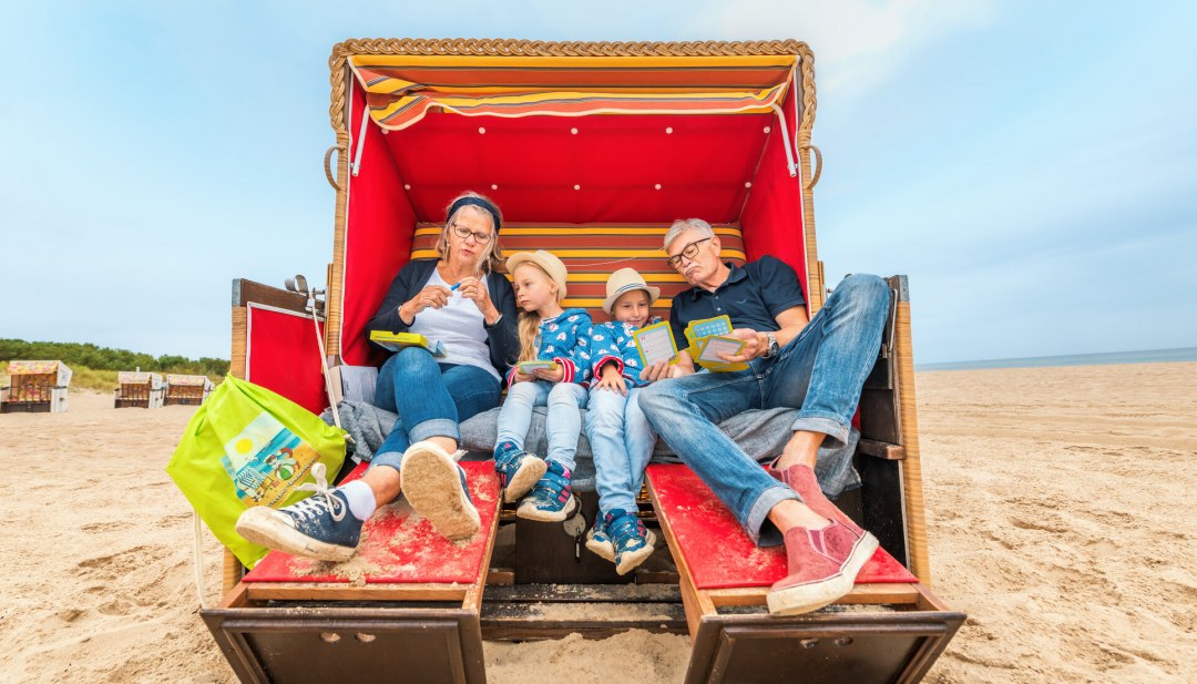 Knuffelen met grootouders in een strandstoel, een zandkasteel bouwen of een pauze nemen voor vakantiefoto's - een dagje strand met grootouders. // &copy; MV-T/Tiemann