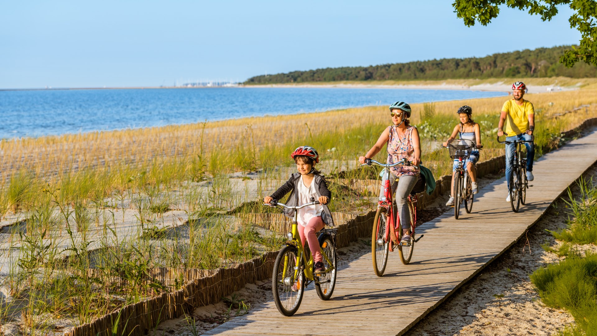 Czteroosobowa rodzina jedzie ścieżką rowerową wzdłuż plaży. // Z Kröslin przez Freest do plaży w Lubminie: Maja jest najszybsza! // © MV-T/Tiemann Czteroosobowa rodzina jedzie ścieżką rowerową wzdłuż plaży.