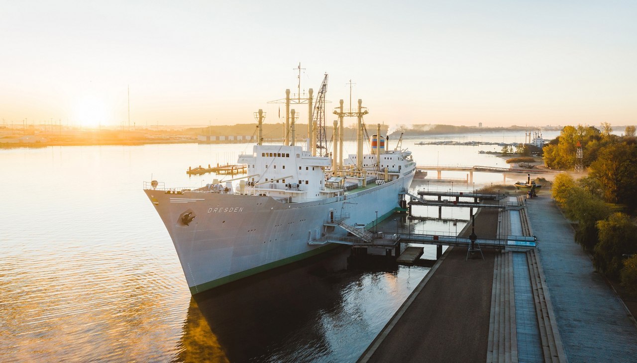 Museumschip Dresden ligt bij zonsopgang afgemeerd in de stadshaven van Rostock en nodigt je uit om de maritieme geschiedenis te ontdekken.