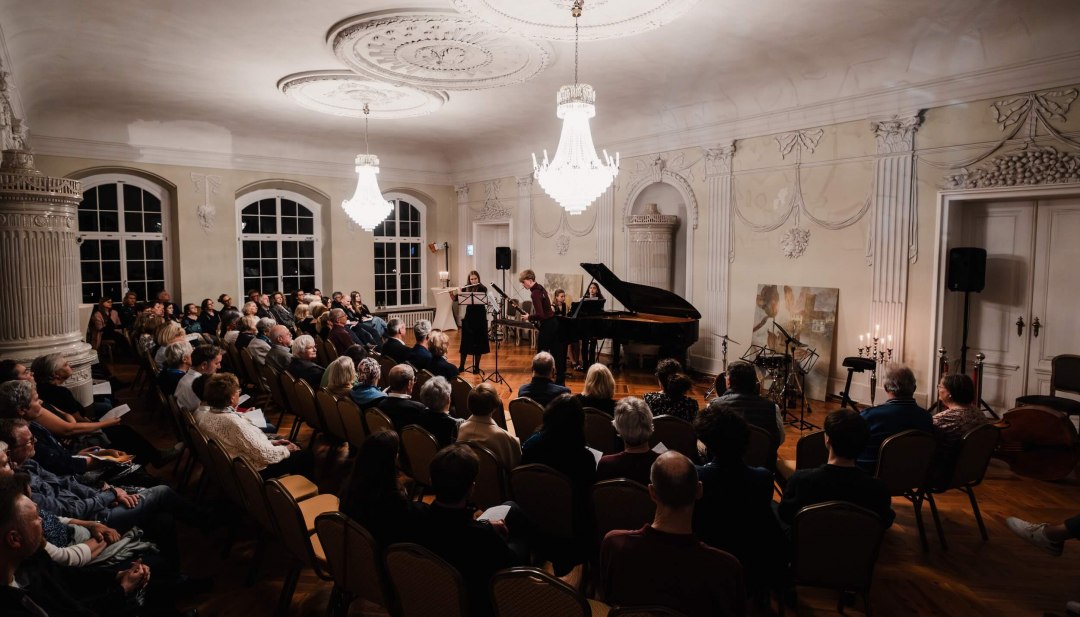 Toeschouwers beleven een klassiek concert in de feestelijk verlichte zaal van kasteel Vietgest tijdens het Schlösserherbst festival.