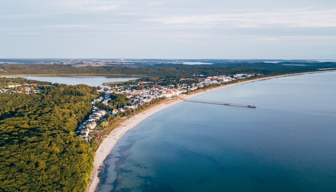 Luchtfoto van Binz op R&uuml;gen met pier, kustlijn en omliggende bossen.