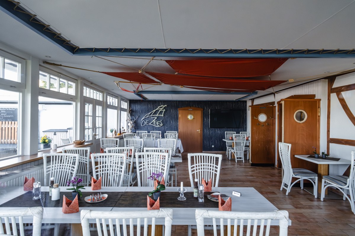 Strefa wypoczynkowa w restauracji DE ZEES w Ribnitz-Damgarten: jasna, przejrzysta, w marynistycznym stylu – miejsce przy oknie i przestrzeń emanująca spokojem. // © Ribnitzer Fischhafen/Hugo Scholz-Witzel Strefa wypoczynkowa w restauracji DE ZEES w Ribnitz-Damgarten: jasna, przejrzysta, w marynistycznym stylu – miejsce przy oknie i przestrzeń emanująca spokojem. // © Ribnitzer Fischhafen/Hugo Scholz-Witzel