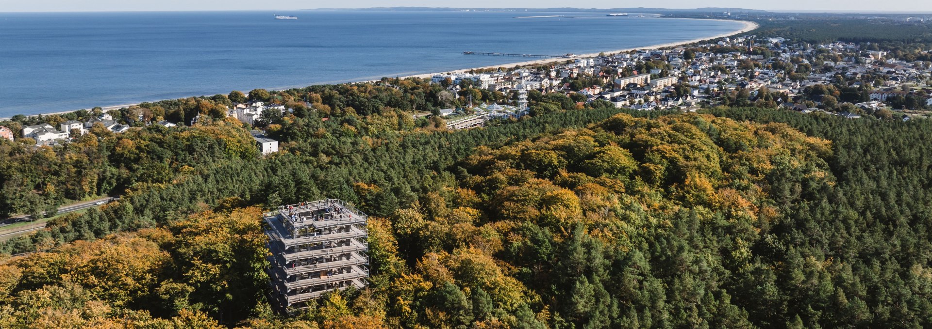 Aerial view of the Usedom treetop walk in the autumn forest with a view of the Baltic Sea coast and the town.