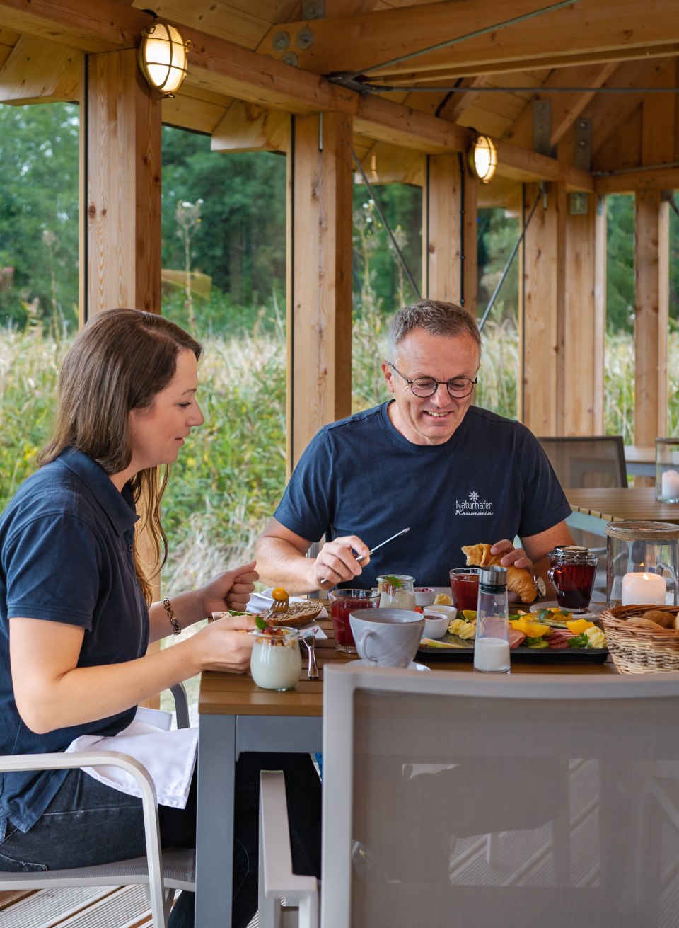 Een koppel zit aan een rijkelijk gedekte ontbijttafel in de natuurlijke haven van Krummin.