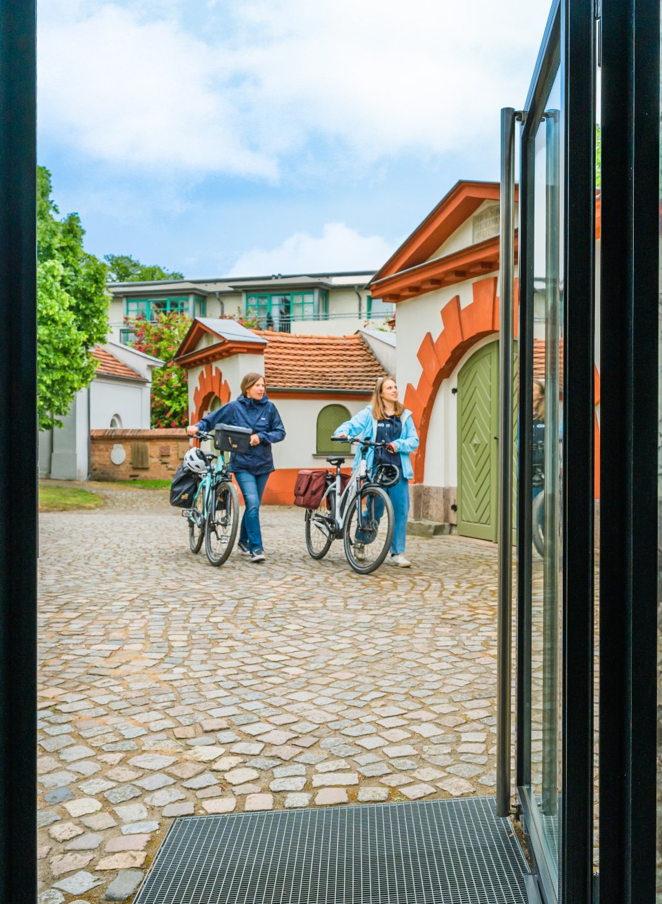 On the way to Ernst Barlach and his sculptures in Güstrow, © TMV/Tiemann Mother and daughter in front of the entrance to the Ernst Barlach exhibition with bicycle