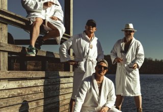 four musicians from the band Herb in white bathrobes on a bathing platform // &copy; Herb Band