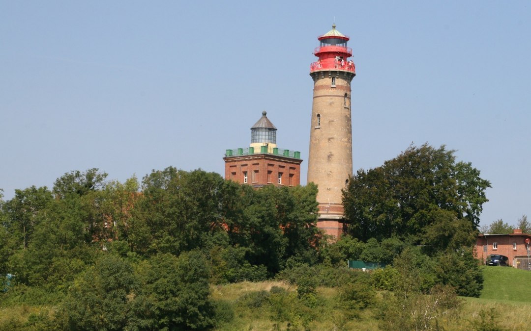 Twee historische vuurtorens bij Kaap Arkona op het eiland Rügen, omgeven door groene natuur en onder een heldere hemel.