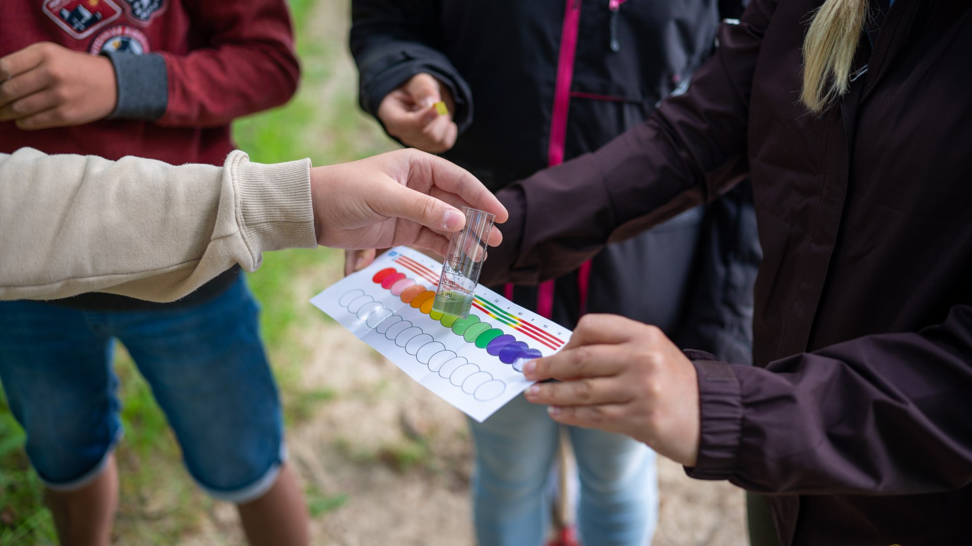 Zeebioloog en leerling onderzoeken de pH-waarde met behulp van een kleurentabel.