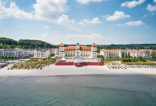 Hotel Kurhaus Binz na Rugii z lotu ptaka z widokiem na plażę od strony morza // Hotel Kurhaus Binz na Rugii // © Kurhaus Binz Hotel Kurhaus Binz na Rugii z lotu ptaka z widokiem na plażę od strony morza