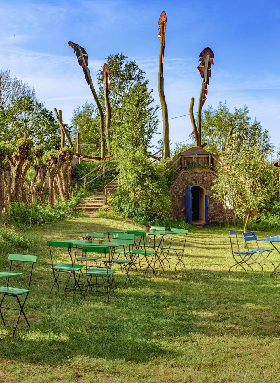 Wangelin tuin en café met hout en boomstammen die de lucht in gaan. De ingang van het café is gemaakt van hout en in een stenen muur die verdwijnt in een heuvel.