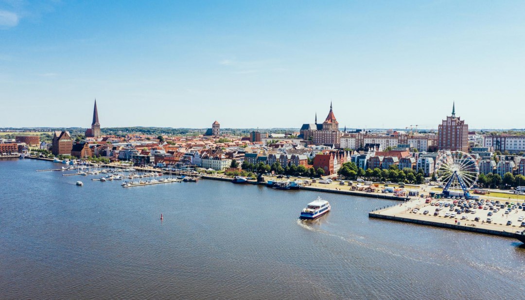 Van bovenaf ziet de stadshaven van Rostock eruit als een miniatuurwonderland. Zelfs het reuzenrad lijkt opeens niet meer zo groot. De excursieboot vaart rustig naar de steiger om nieuwe passagiers op te pikken., &copy; TMV/G&auml;nsicke