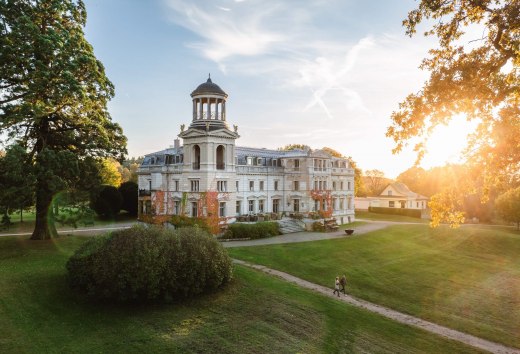 Kasteel Kaarz in Mecklenburg-Schwerin bij zonsondergang met wandelaars in het goed onderhouden kasteelpark.