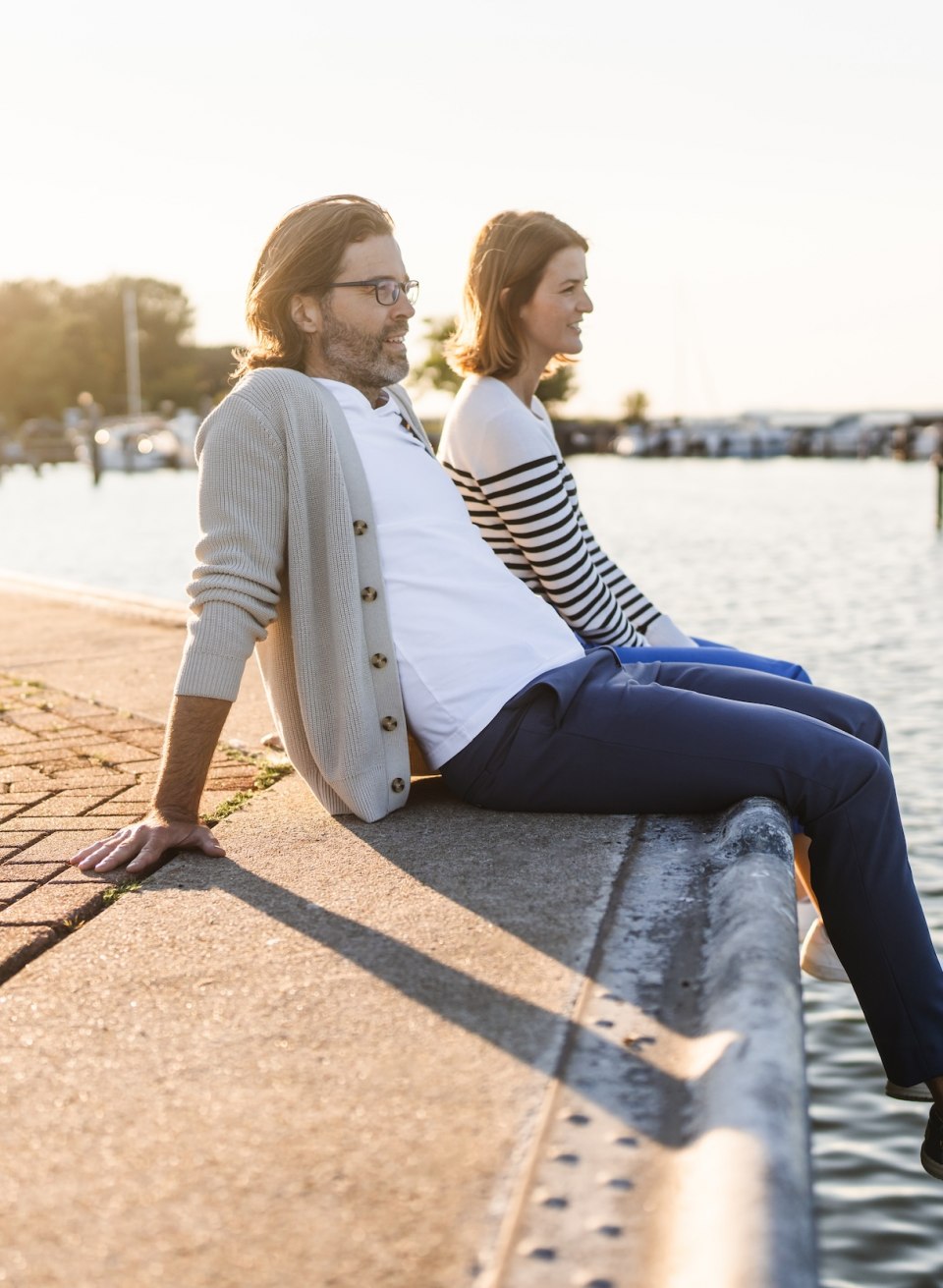 It doesn't get much more romantic than a sunset on the shores of the Baltic Sea., © TMV/Gross Stahlbrode ferry pier - a couple sits by the water at the edge of the harbor at sunset