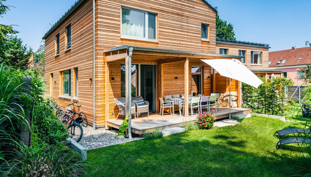 Een vakantiehuis met houten lambrisering en een groene weide ervoor.