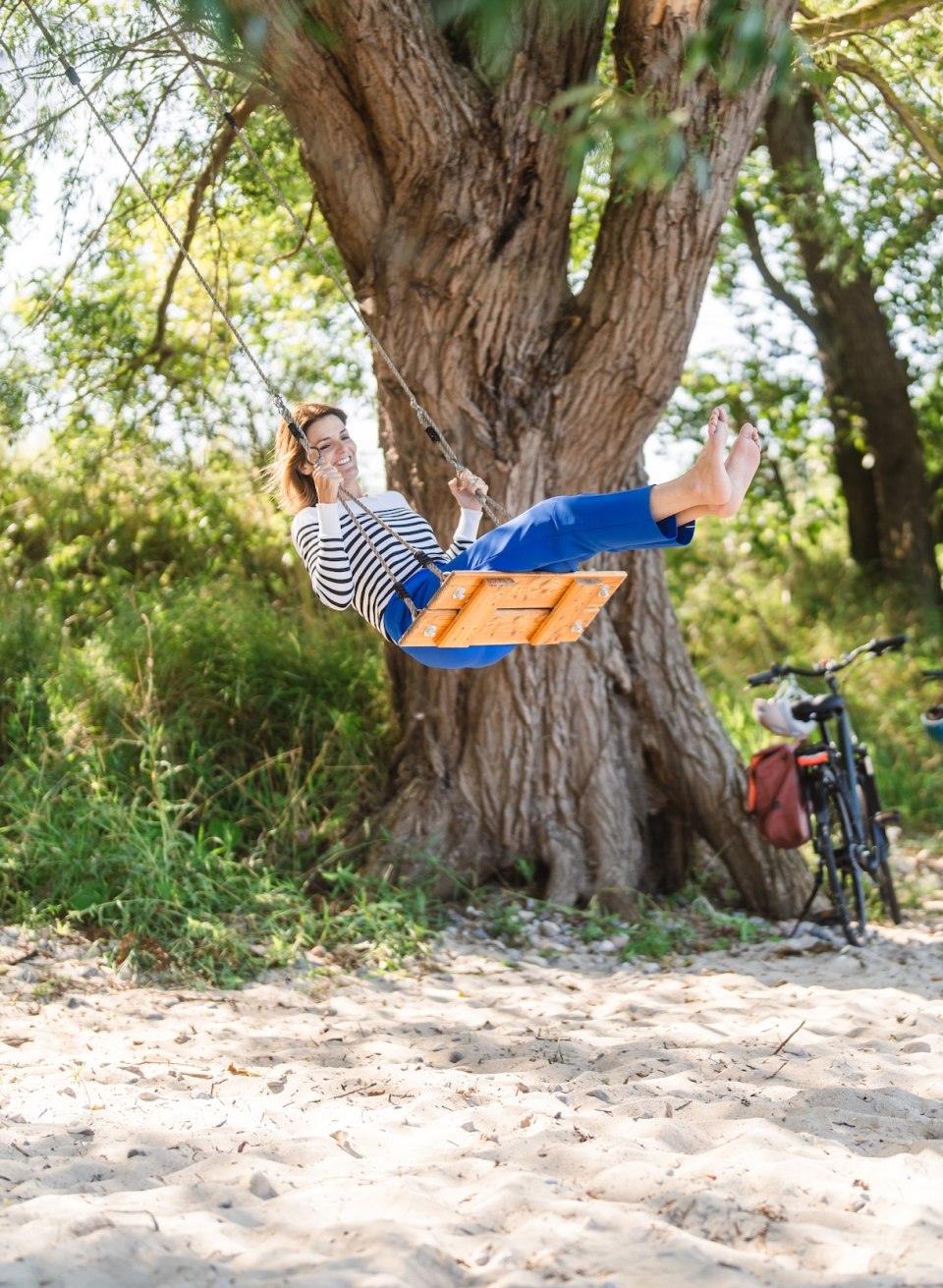 A woman swings on the beach under a tree near Lubmin.