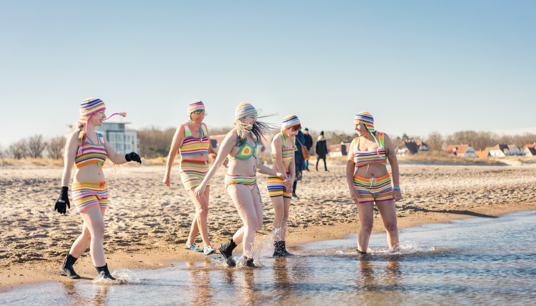 IJsbaders nemen een duik in de Baltische Zee op het strand van Warnemünde in de zon.