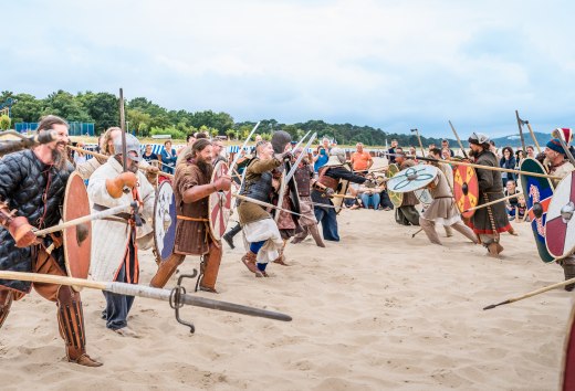 Mensen verkleed als Vikingen rennen naar elkaar toe op het strand van Göhren
