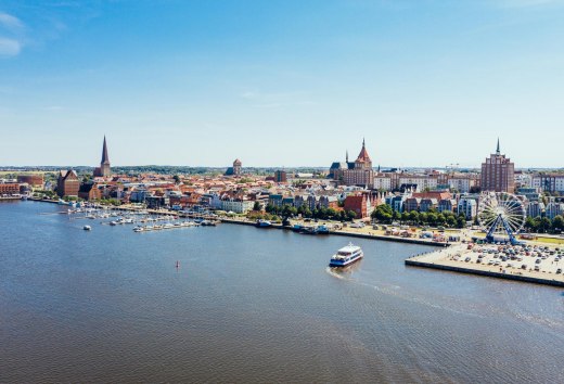 Van bovenaf ziet de stadshaven van Rostock eruit als een miniatuurwonderland. Zelfs het reuzenrad lijkt opeens niet meer zo groot. De excursieboot vaart rustig naar de steiger om nieuwe passagiers op te pikken., © TMV/Gänsicke