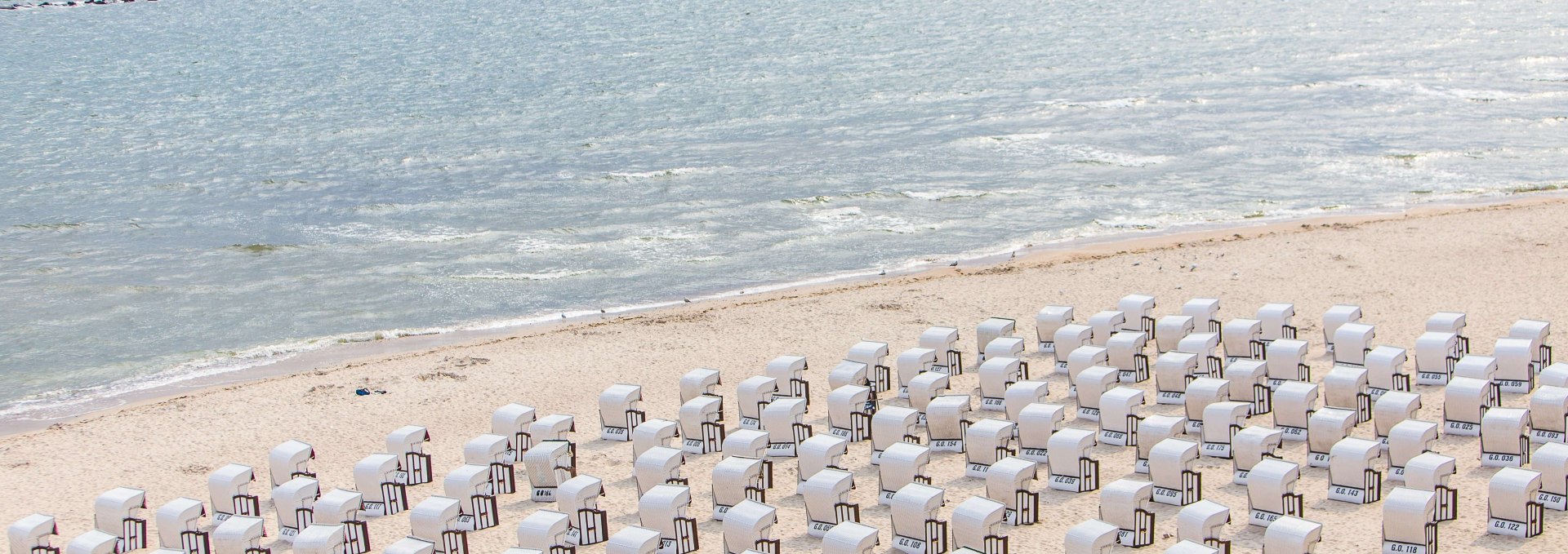 Witte strandstoelen staan als kleine miniatuurfiguurtjes langs het strand van Sellin., © TMV/Krauss