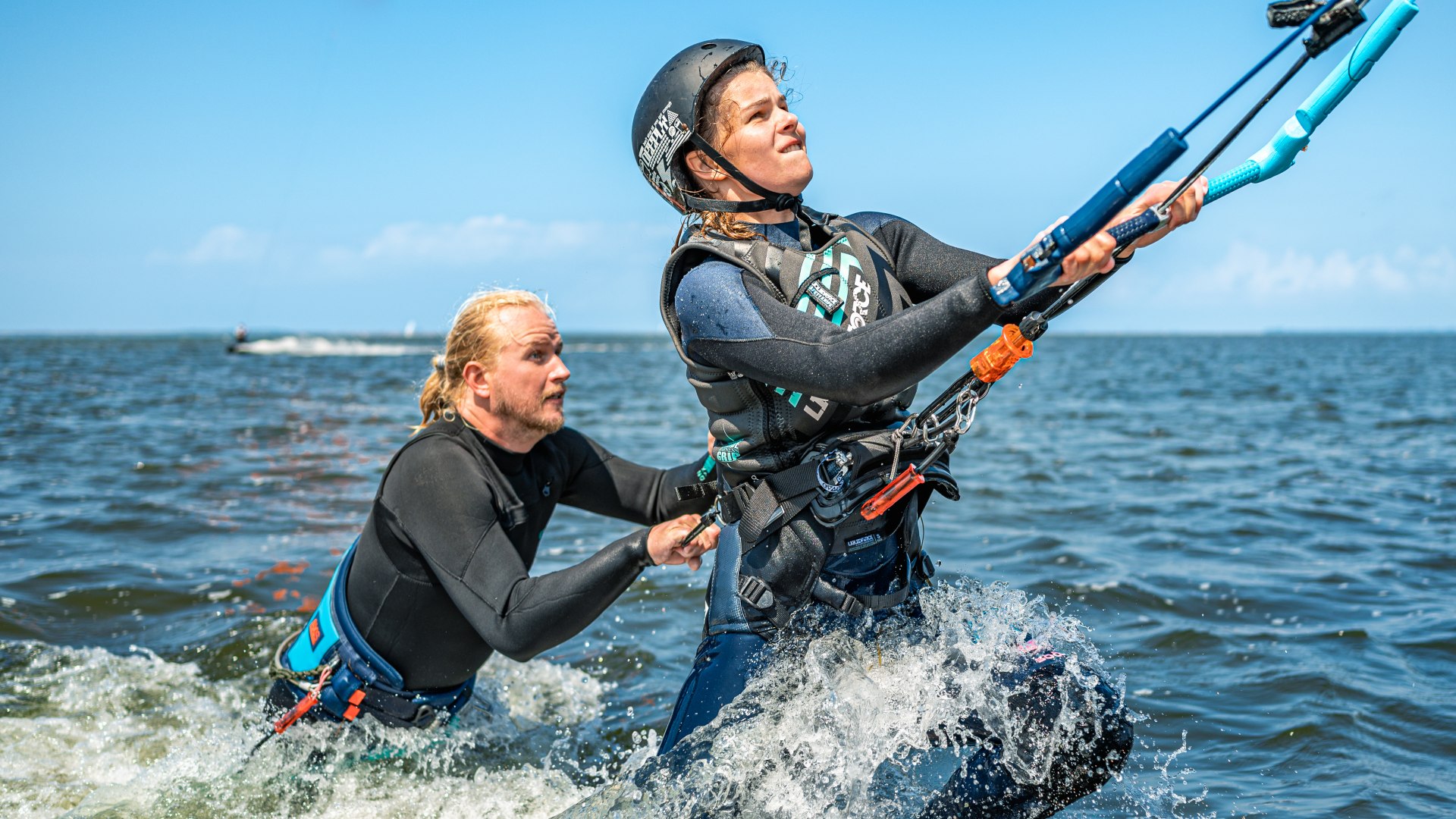 De vlieger trekt Luisa uit het water. De vliegerinstructeur houdt haar stevig vast.