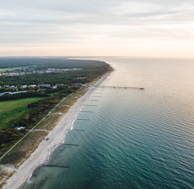 Aerial view of the pier and the beach of Graal-M&uuml;ritz, surrounded by woods and meadows, with the Baltic Sea in the light of an atmospheric sunset.
