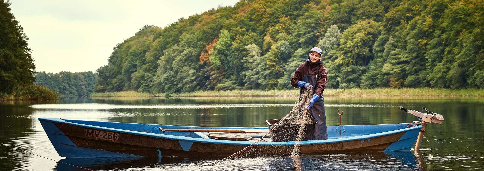 Fisherman in the Mecklenburg Lake District is pulling his nets onto the boat.