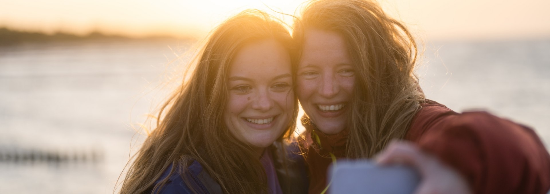 Een winderige selfie aan het einde is een must! Je kunt letterlijk het plezier van Linda en Marie zien op hun gezichten. Bij zonsondergang beëindigen de twee wandelaars hun tocht op het natuurparkpad op de pier in Koserow.  , © TMV/Gross