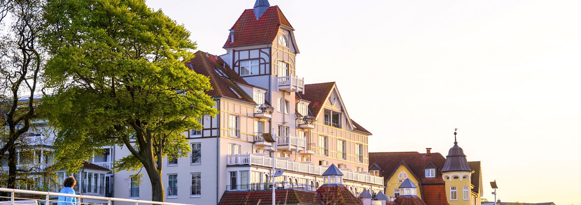 Historic spa architecture in Kühlungsborn - charming villas in the evening light, surrounded by dunes and promenade, invite you to take a stroll., © TFK/Jasmin Fernholz Elegant spa-style villa in Kühlungsborn, surrounded by dunes and trees, in the warm light of the evening sun.