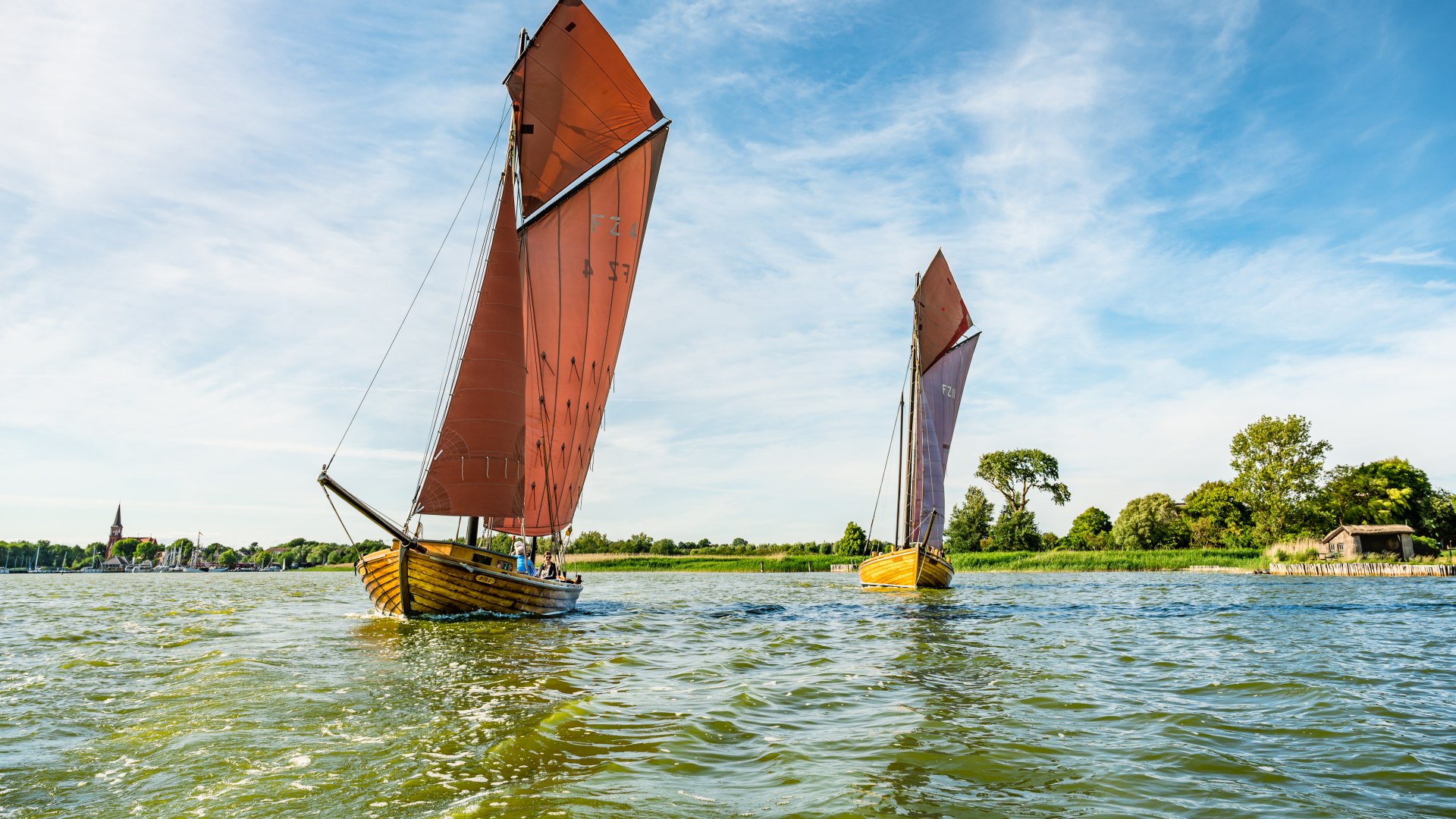 Łodzie Zeesboote suną po wodzie z powiewającymi brązowymi żaglami. // © MV-T/Tiemann Łodzie Zeesboote suną po wodzie z powiewającymi brązowymi żaglami. // © MV-T/Tiemann