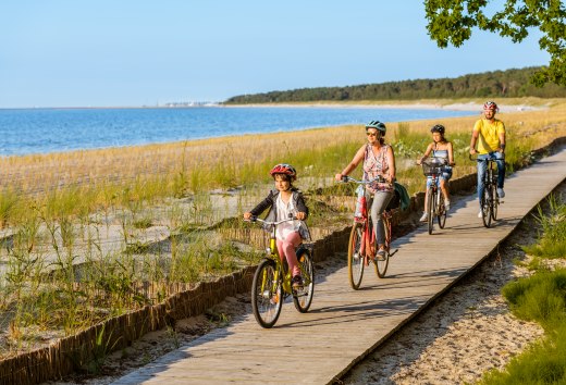 Een gezin van vier fietst over het fietspad op het strand.