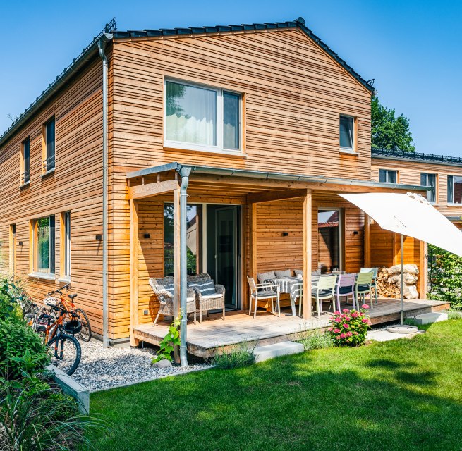 Een vakantiehuis met houten lambrisering en een groene weide ervoor.