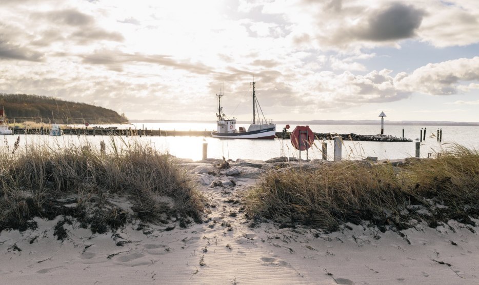 Spacer wzdłuż plaży z widokiem na ł&oacute;dź rybacką na Morzu Bałtyckim w porcie Timmendorf na wyspie Poel. // &copy; MV-T/Meckel