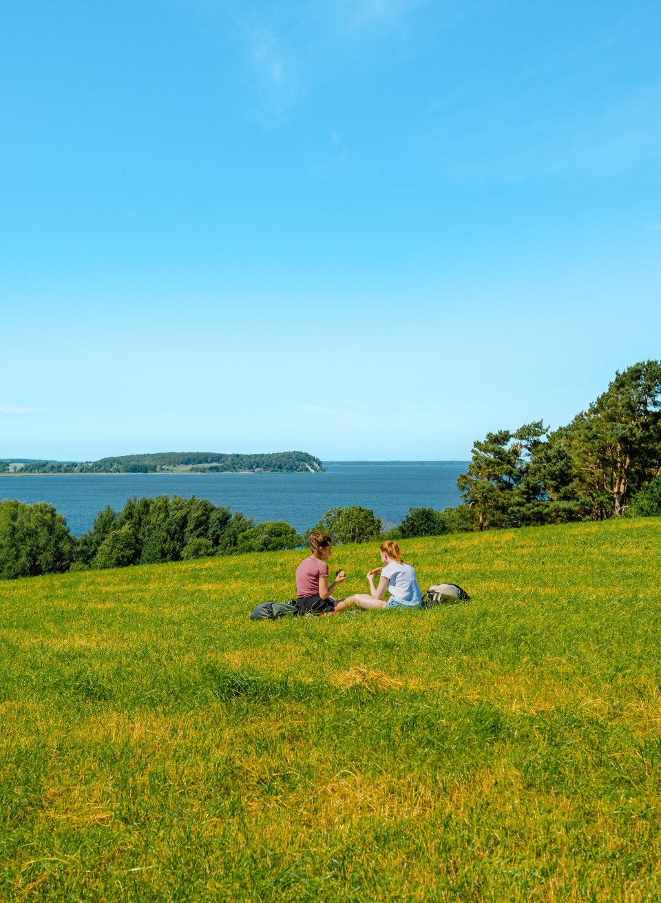 Two women picnicking on a meadow with a view of the Jasmund Bodden