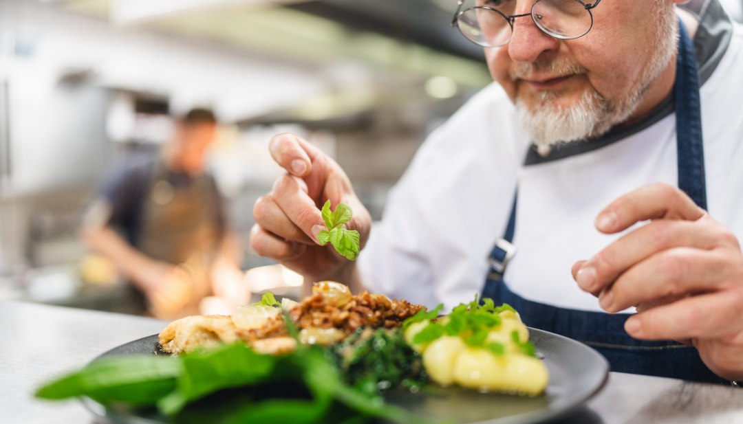 With a final touch, Frank Haarde places the wild herbs on the freshly caught plaice., © TMV/Gross With a final touch, Frank Haarde places the wild herbs on the freshly caught plaice.
