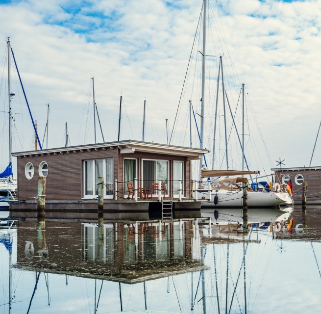 Woonboten en zeilboten aangemeerd in de haven van Krummin // Drijvend vakantiegeluk: De suites, ontworpen in de stijl van woonboten, zijn stevig verankerd. // © MV-T/Tiemann Woonboten en zeilboten aangemeerd in de haven van Krummin