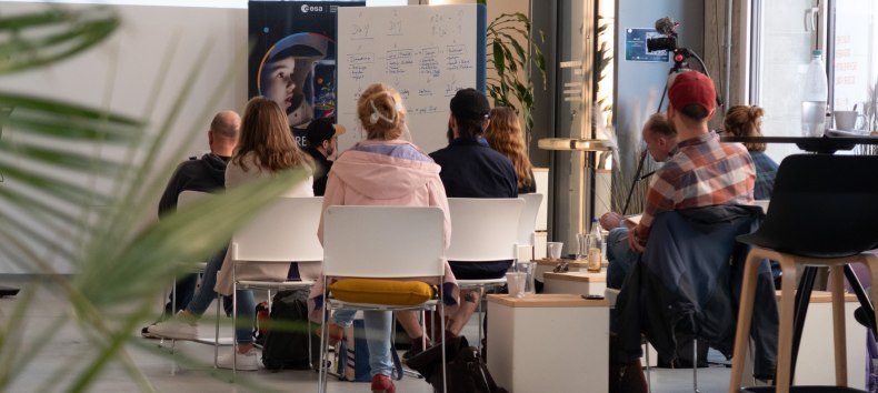Workshop group seen from behind at InnovationPort Wismar in front of a whiteboard and roll-up banner // © InnovationPort Wismar Workshop group seen from behind at InnovationPort Wismar in front of a whiteboard and roll-up banner // © InnovationPort Wismar