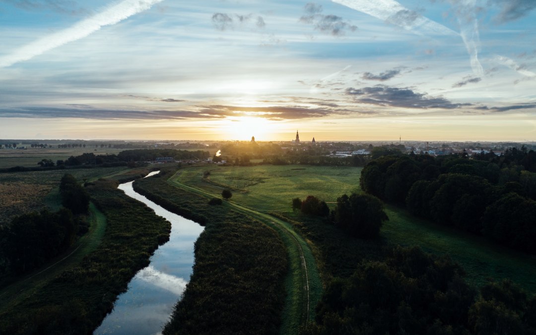 Sunrise over the Hanseatic City of Greifswald: a quiet river meanders through meadows, while church spires slowly become visible in the morning light on the horizon. Mecklenburg-Vorpommern awakens quietly. // &copy; MV-T/G&auml;nsicke