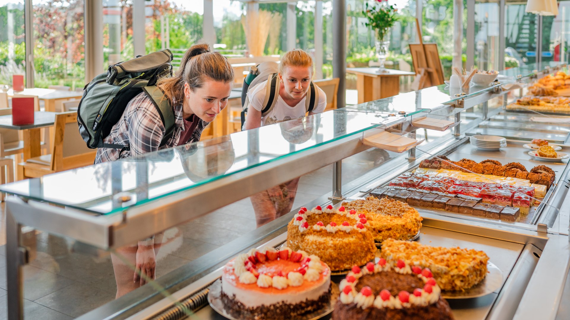 Twee vrouwen kijken door de vitrine bij een taartenbuffet in de bakkerij