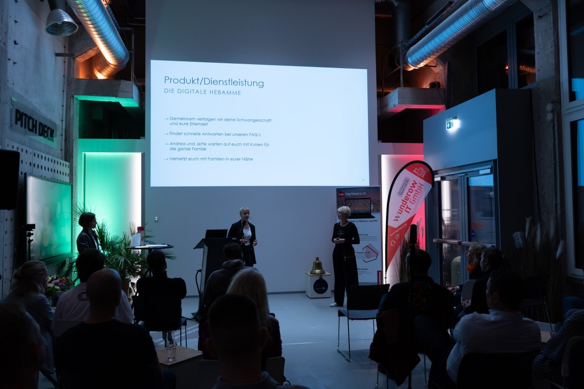 Evening event at InnovationPort Wismar, with the audience seated at the back in front of the screen // © InnovationPort Wismar Evening event at InnovationPort Wismar, with the audience seated at the back in front of the screen // © InnovationPort Wismar