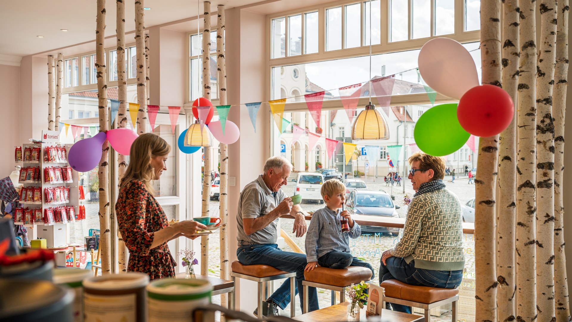 Grandparents and grandchildren drink coffee at the high table with a view outside.