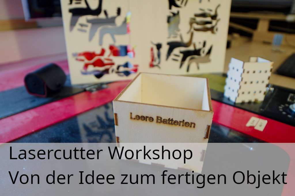 Multiplex lasergesneden doos met het label "Lege batterijen" met andere lasergesneden onderdelen en de lasersnijder zelf op de achtergrond, &copy; Hacklabor.de