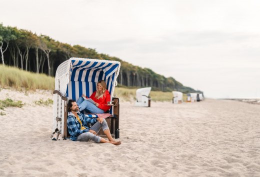 Couple sitting in a beach chair on the beach at Graal-Müritz on the Baltic Sea coast. The coastal forest can be seen in the background. // A couple sits in a beach chair on the beach in Graal-Müritz // © MV-T/Gross Couple sitting in a beach chair on the beach at Graal-Müritz on the Baltic Sea coast. The coastal forest can be seen in the background.