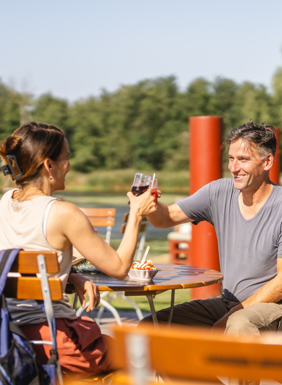 A couple enjoy a refreshment and a snack in the outdoor area of the Stolper F&auml;hrkrug with a view of the Peene.
