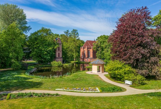 Klokkentoren en parkgebouw in de paleistuinen van Ludwigslust met bloemen en bomen.
