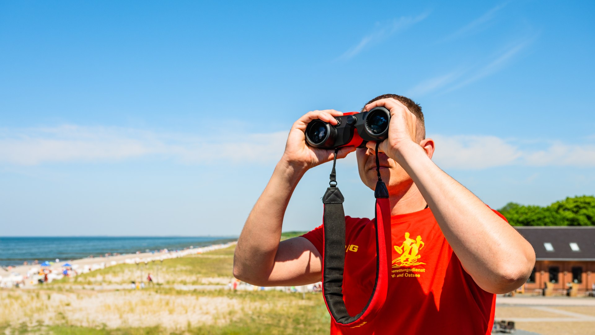 Badmeester met verrekijker kijkt in de verte