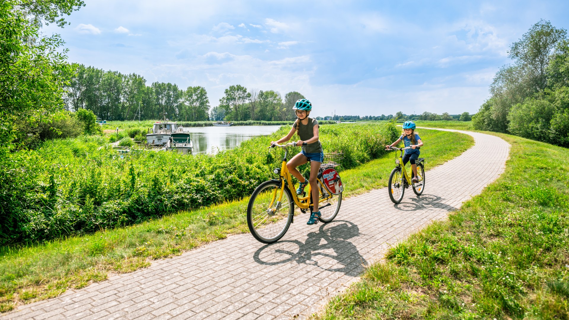 You can also cycle along the Achterwasser., © TMV/Tiemann Two children ride along the Achterwasser on yellow bicycles